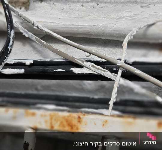 חוטים וצינורות עם חומר איטום לבן על קיר חיצוני